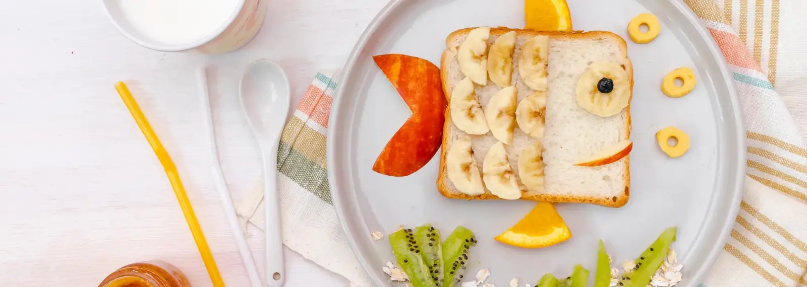 Esmorzar infantil: torrada amb forma de peix decorada amb plàtan, taronja, kiwi i civada