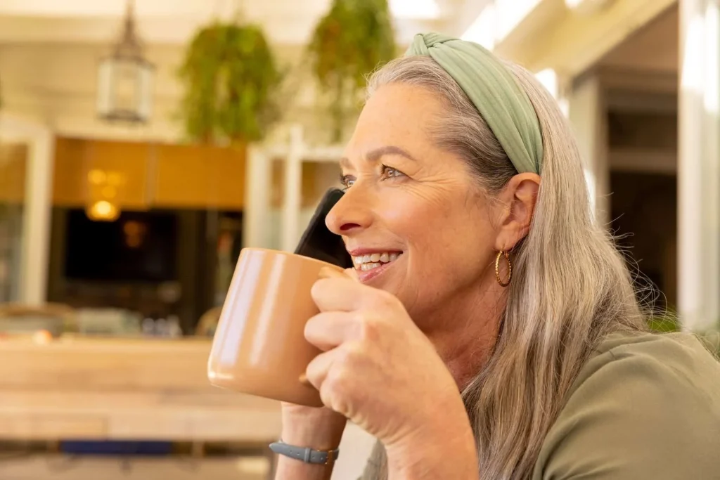 Mujer sonriente con una taza hablando por teléfono